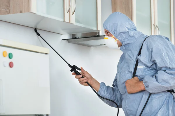 Exterminador en pulverización de plaguicidas en la cocina — Foto de Stock