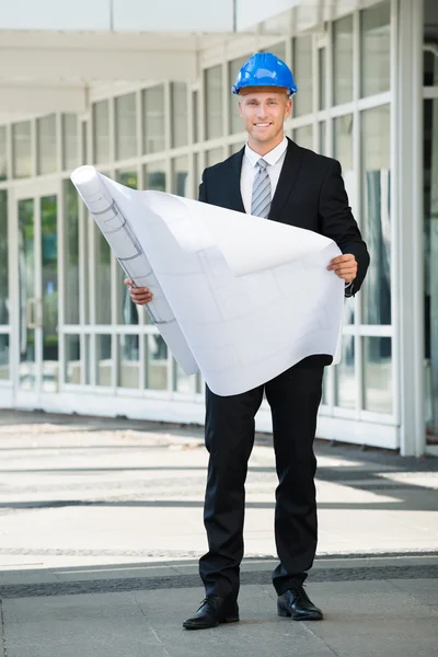 Ingeniero sonriente sosteniendo impresión azul — Foto de Stock