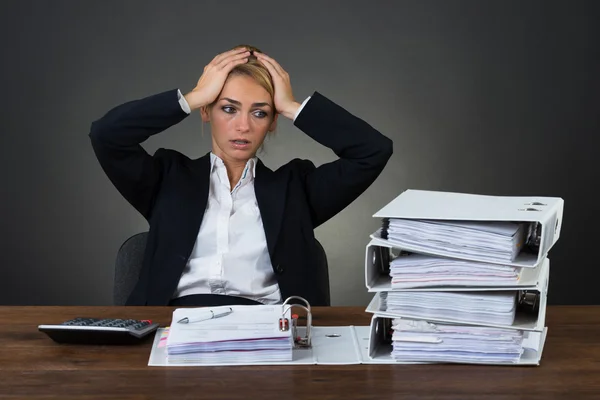 Mujer de negocios cansada con las manos en la cabeza en el escritorio —  Fotos de Stock