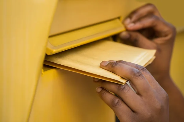 Person legt Brief von Hand in Briefkasten — Stockfoto