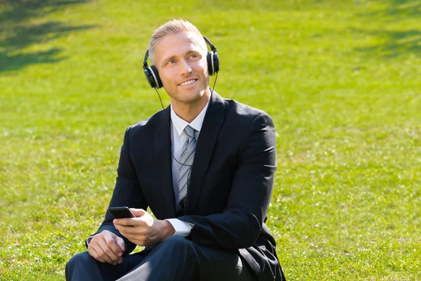 Empresario escuchando música en el parque —  Fotos de Stock