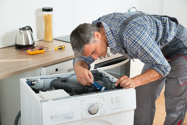 Handyman vérification machine à laver avec lampe de poche — Photo