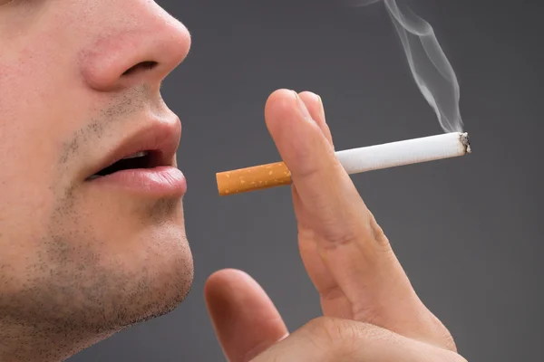 Hombre fumando contra fondo gris — Foto de Stock