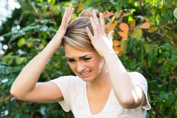 Vrouw met handen op hoofd tegen planten — Stockfoto