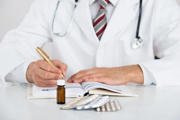 Midsection Of Doctor Writing Prescription At Table — Stock Photo, Image