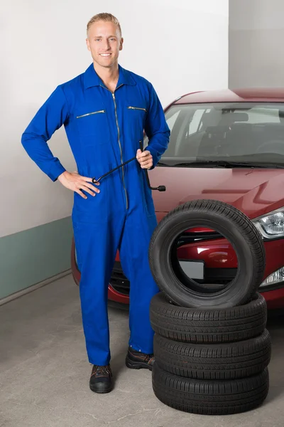 Mécanicien debout à côté des pneus — Photo