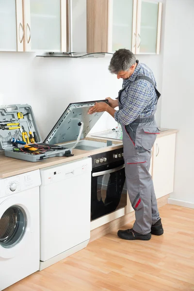 Réparateur examinant cuisinière dans la cuisine — Photo