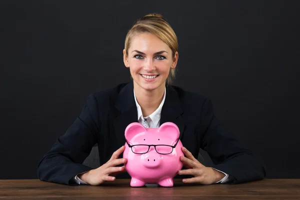 Empresária sorridente com Piggybank na mesa — Fotografia de Stock