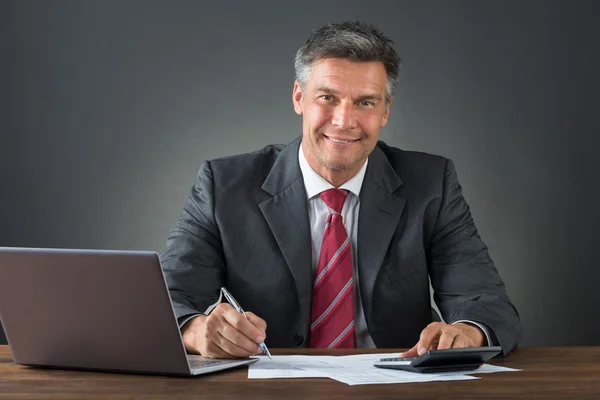 Affärsman Kontrollera räkningar vid skrivbord — Stockfoto