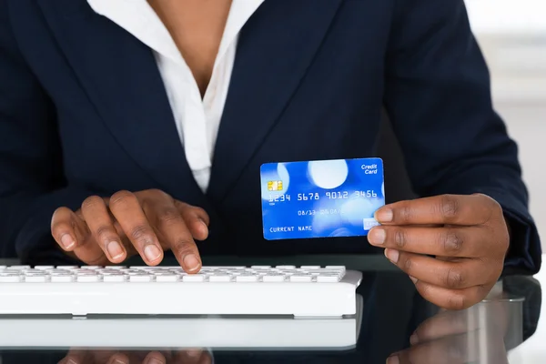 Hålla kreditkort när du skriver på tangentbordet — Stockfoto