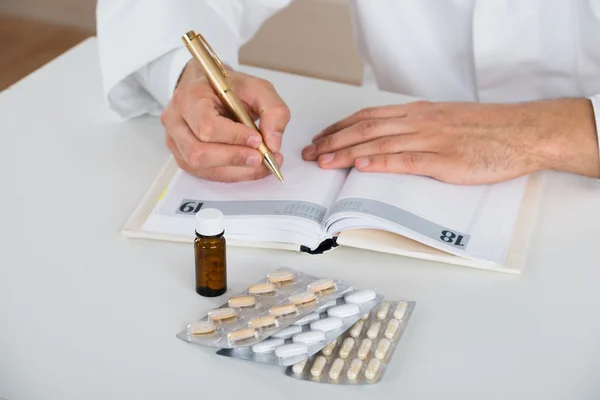 Lekarz pisze receptę na stole w klinice — Zdjęcie stockowe