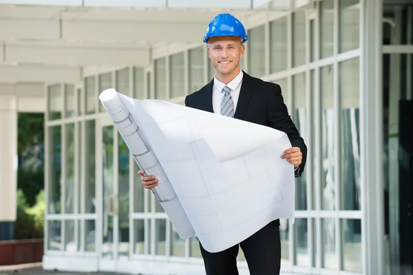 Ingeniero sonriente sosteniendo impresión azul — Foto de Stock