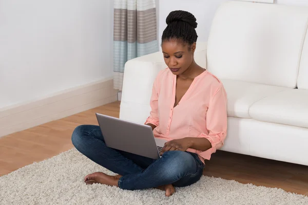 Wanita yang duduk di karpet menggunakan laptop — Stok Foto