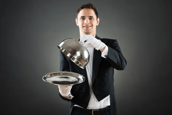 Garçom segurando Cloche sobre bandeja vazia — Fotografia de Stock