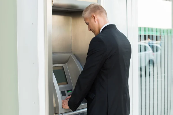 Jovem homem usando máquina de ATM — Fotografia de Stock