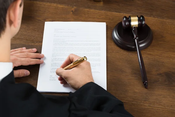 Juez escribiendo sobre documentos legales en la sala del tribunal — Foto de Stock