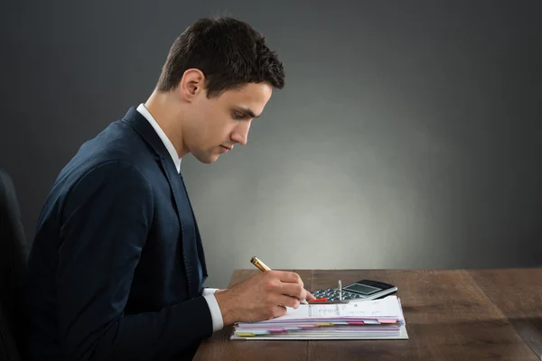 Businessman Examining Invoice At Desk — Stock Photo, Image