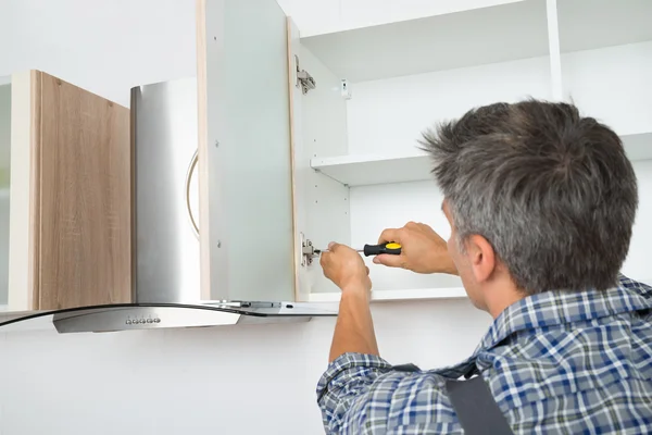 Serviceman Fixing Cabinet With Screwdriver In Kitchen — Stock Photo, Image