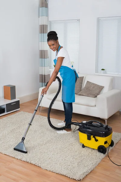 Frau putzt Teppich mit Staubsauger — Stockfoto