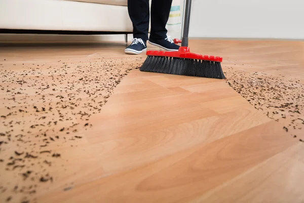 Koště čištění špínu na dřevěnou podlahu — Stock fotografie