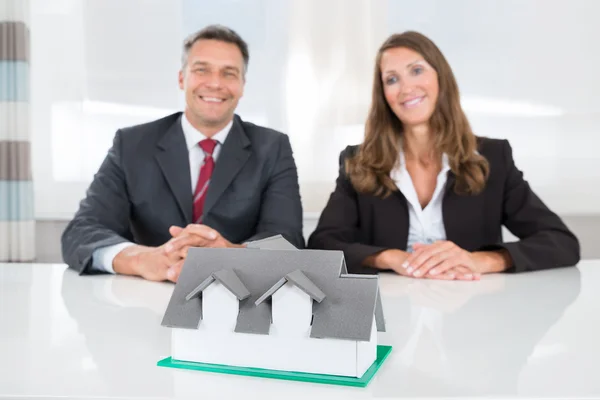 Biznesmeni, patrząc na dom Model na biurko — Zdjęcie stockowe