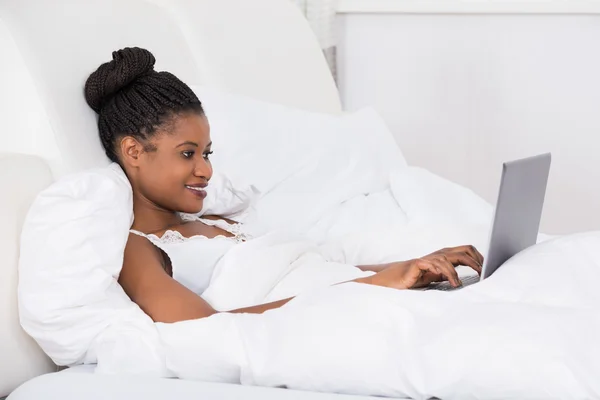 Mujer usando portátil en la cama —  Fotos de Stock