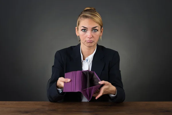 Geschäftsfrau zeigt leere Kupplung am Schreibtisch — Stockfoto