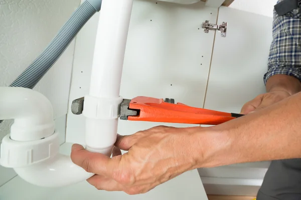 Manutentore che fissa il tubo del lavandino in cucina — Foto Stock
