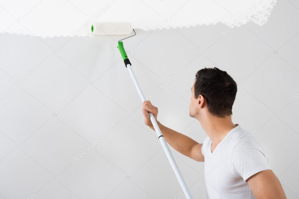 Man Painting Wall With Paint Roller