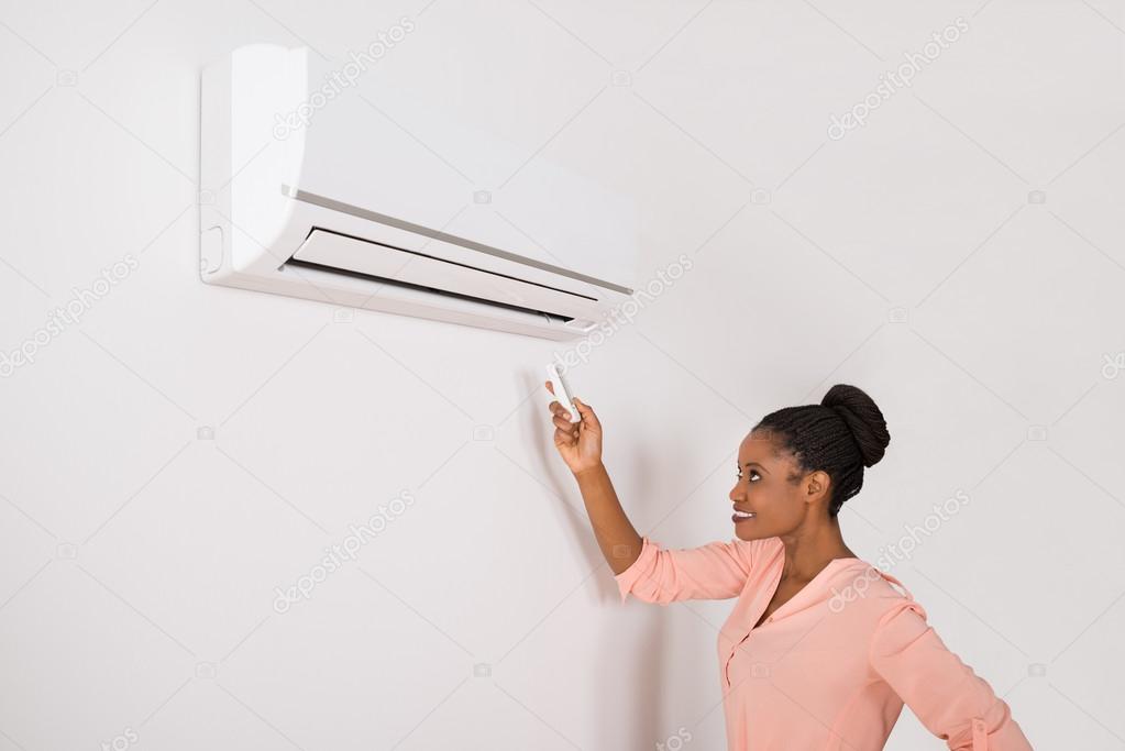 Smiling Woman Operating Air Conditioner