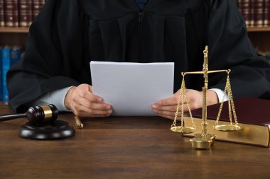 Mahkeme salonunda masada yargıç okuma makaleler