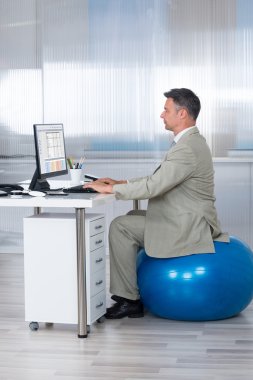 Egzersiz topu üzerinde otururken bilgisayar kullanarak