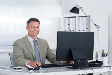 Masa başında bilgisayarla emin iş adamı