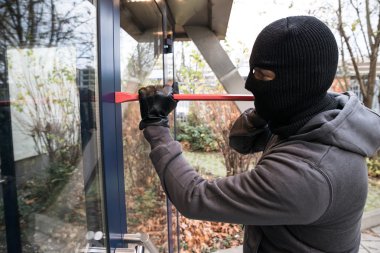 Man Using Crowbar To Open Door clipart