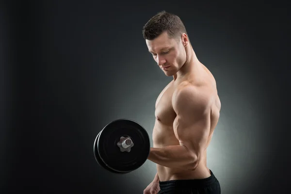 Homem muscular confiante levantando halteres — Fotografia de Stock