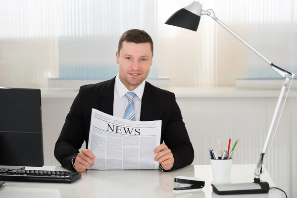 Biznesmen trzymając gazetę na biurku w biurze — Zdjęcie stockowe
