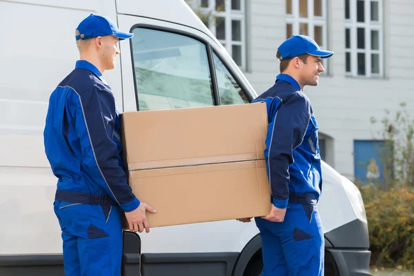 Homens de entrega transportando caixa de papelão — Fotografia de Stock
