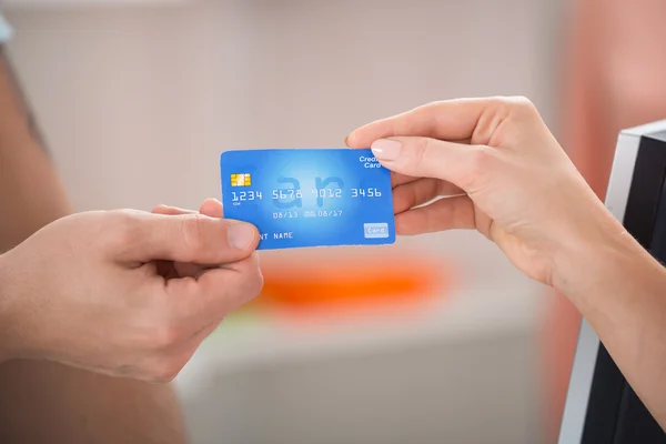 Vendedor tomando cartão de crédito do cliente — Fotografia de Stock