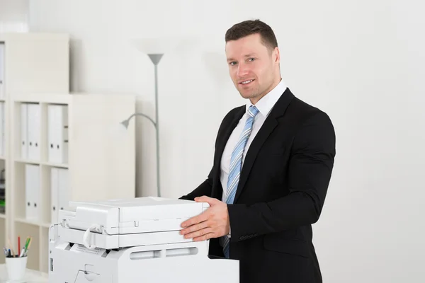 Empresario seguro de pie junto a la máquina de fotocopia —  Fotos de Stock