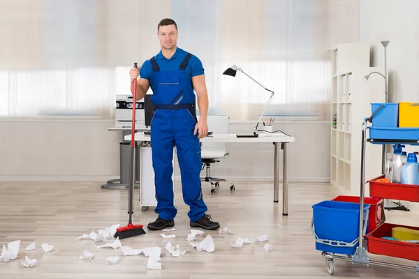 Janitor piso de limpeza com vassoura no escritório — Fotografia de Stock