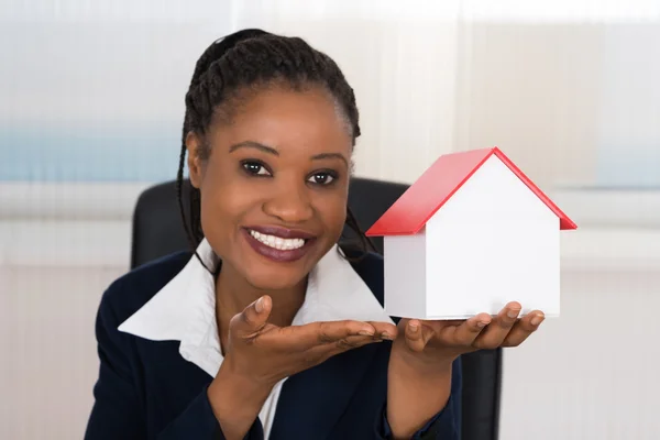 Empresária apresentando um modelo de casa — Fotografia de Stock