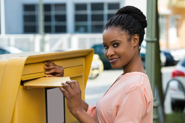 Женщина вставляет письмо в почтовый ящик — стоковое фото