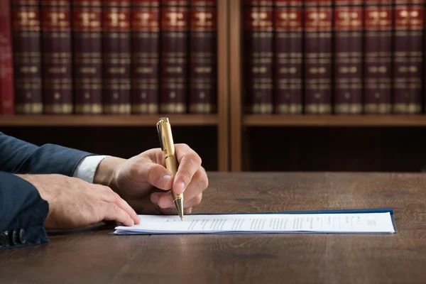 Abogado escribiendo sobre documentos legales en el escritorio — Foto de Stock