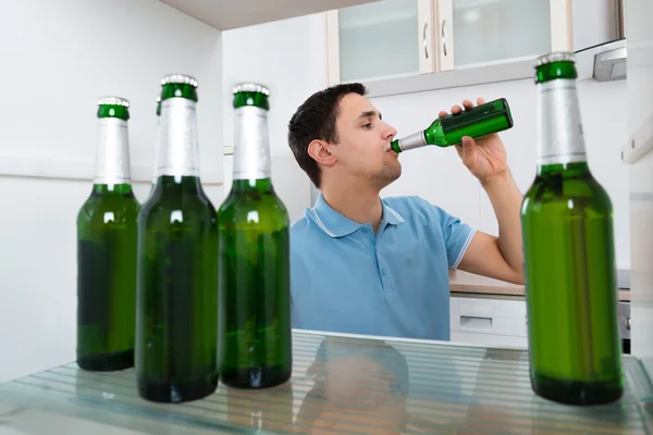 Uomo che beve birra davanti al frigorifero — Foto Stock