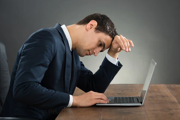 Стресс бизнесмен с помощью ноутбука на рабочем столе — стоковое фото