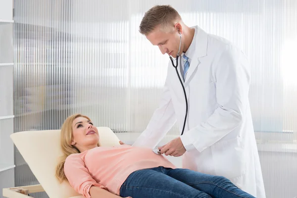 Médico examinando mulher grávida com estetoscópio — Fotografia de Stock