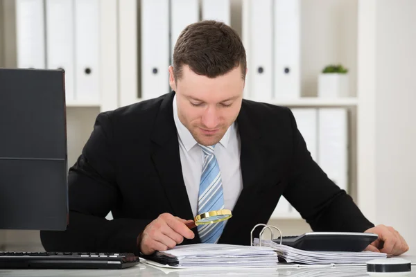 Accountant analyseren factuur met Vergrootglas — Stockfoto