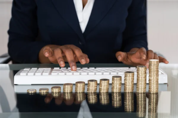 Persona que usa el teclado delante de la pila de monedas — Foto de Stock