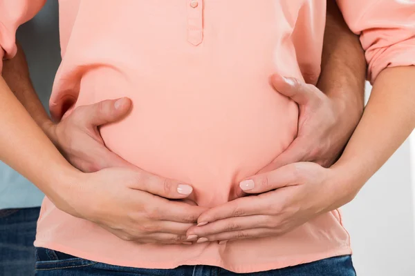 Пара с руками на беременном животе — стоковое фото