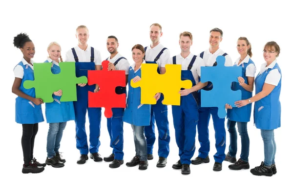 Janitors Holding Jigsaw Pieces In Row — Stock Photo, Image